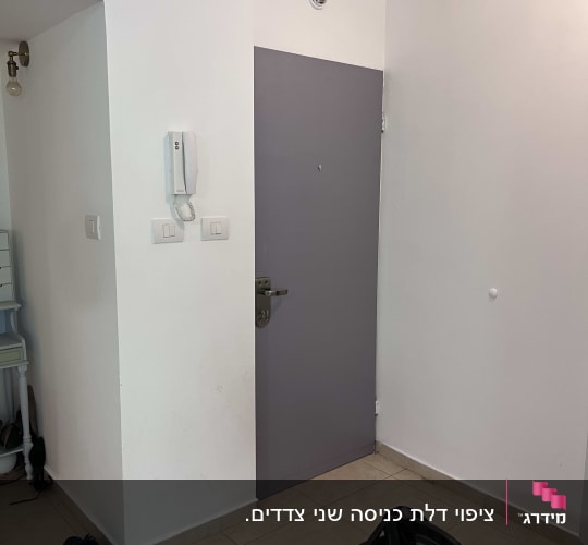 דלת אפורה עם ידית מתכת על קיר לבן